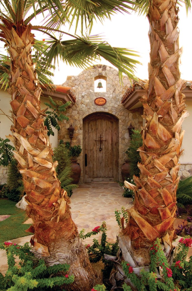 Esempio di una grande porta d'ingresso tropicale con una porta singola e una porta in legno chiaro