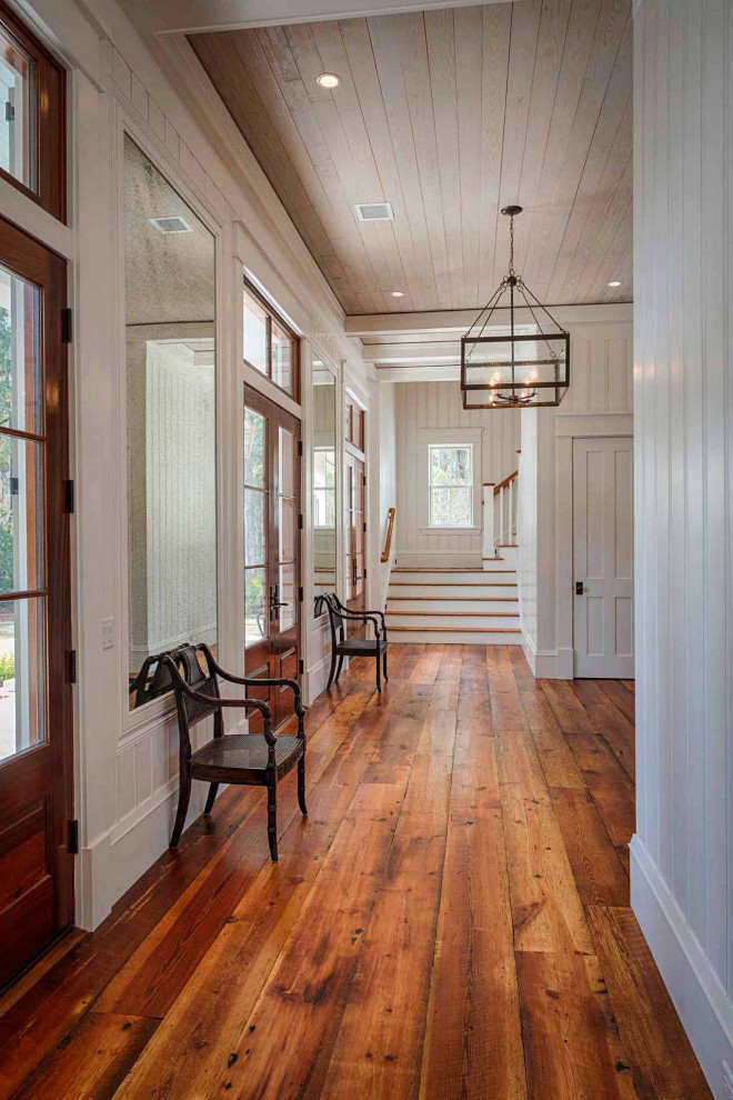 Foyer mit weißer Wandfarbe, braunem Holzboden, Doppeltür, hellbrauner Holzhaustür, braunem Boden, Holzdielenwänden und Kassettendecke in Sonstige