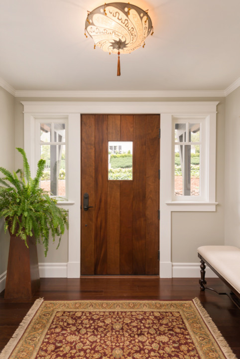 Cette image montre une entrée traditionnelle avec un mur beige, parquet en bambou, une porte simple et une porte en bois brun.