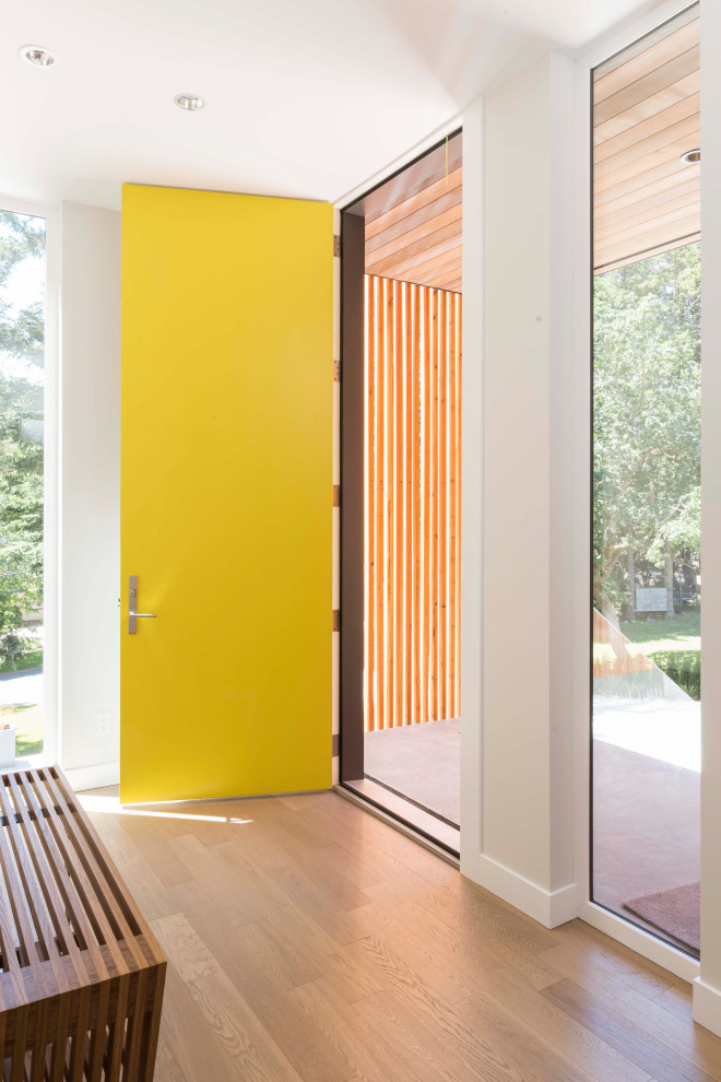 Imagen de puerta principal moderna grande con paredes blancas, suelo de madera clara, puerta simple, puerta amarilla y suelo beige