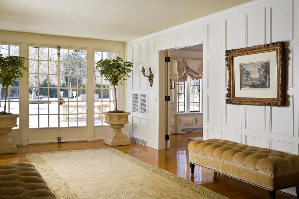 Cette photo montre un très grand hall d'entrée chic avec un mur blanc et un sol en bois brun.