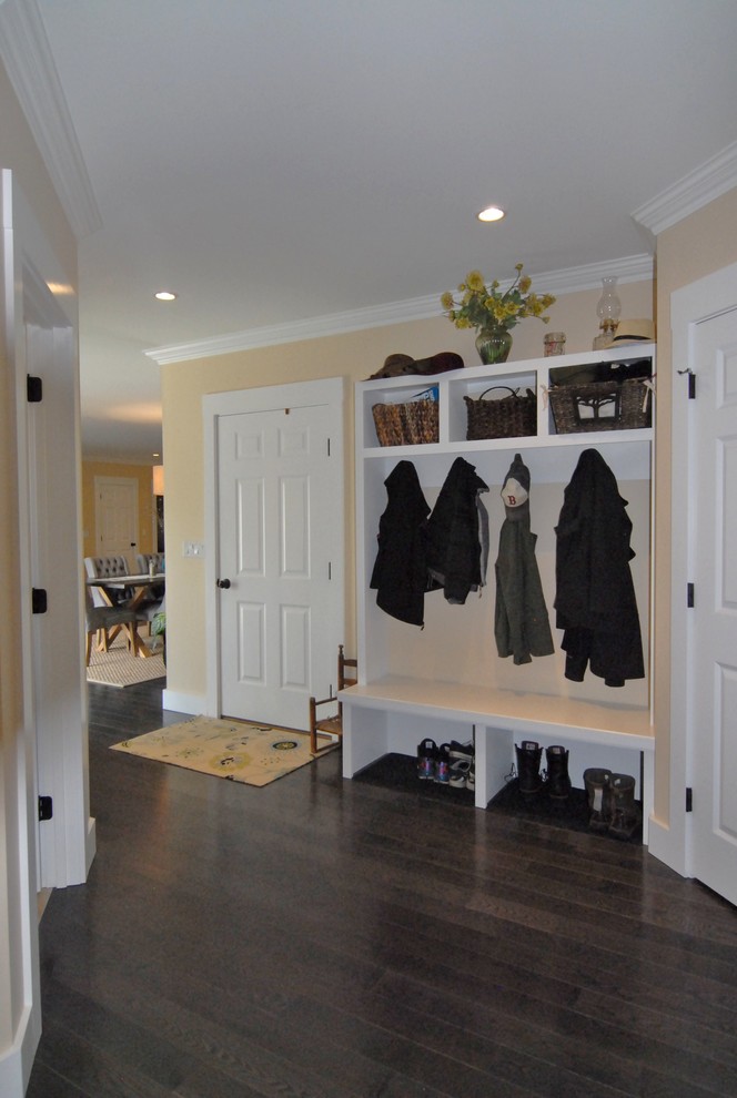 Cette photo montre une entrée chic avec un mur beige, parquet foncé, un vestiaire, une porte simple et une porte en bois brun.