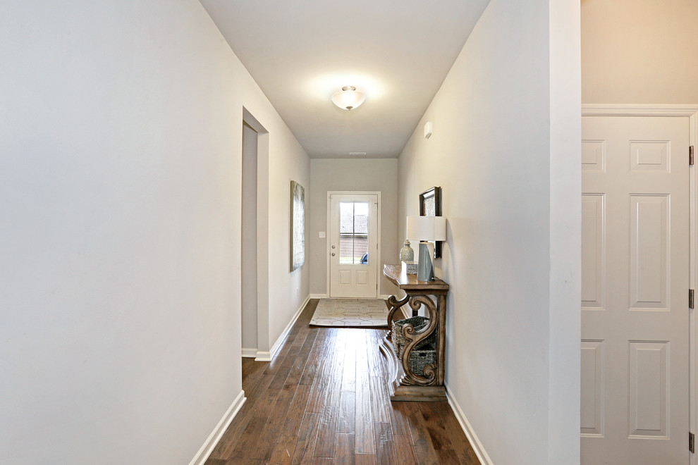 Example of a transitional medium tone wood floor entryway design in Other with gray walls and a white front door