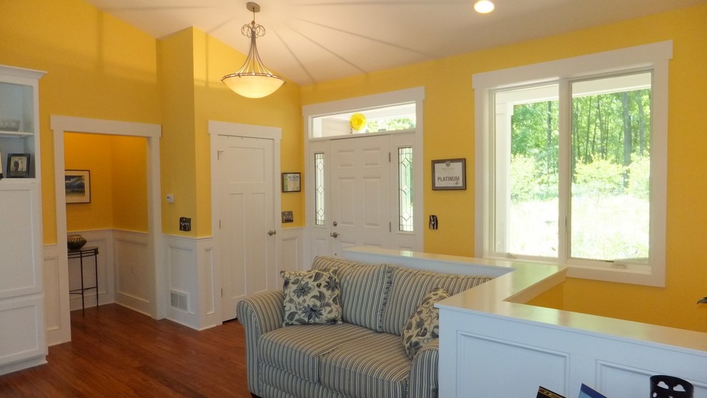 Idéer för en klassisk foajé, med gula väggar, ljust trägolv, en enkeldörr och en vit dörr