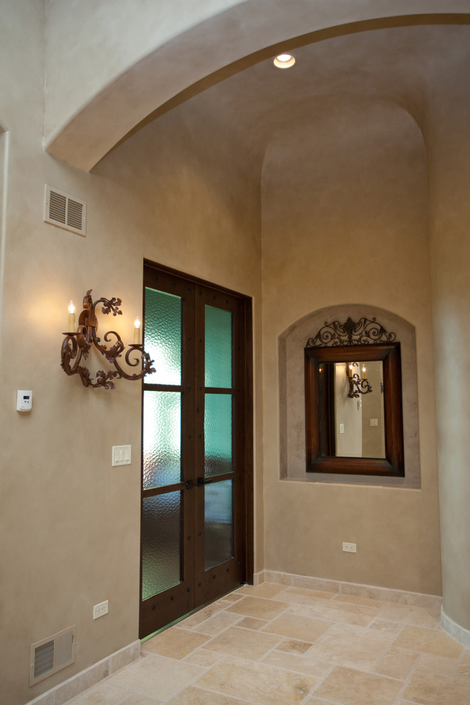 This is an example of a large mediterranean foyer in Chicago with beige walls, limestone flooring, a single front door and a metal front door.
