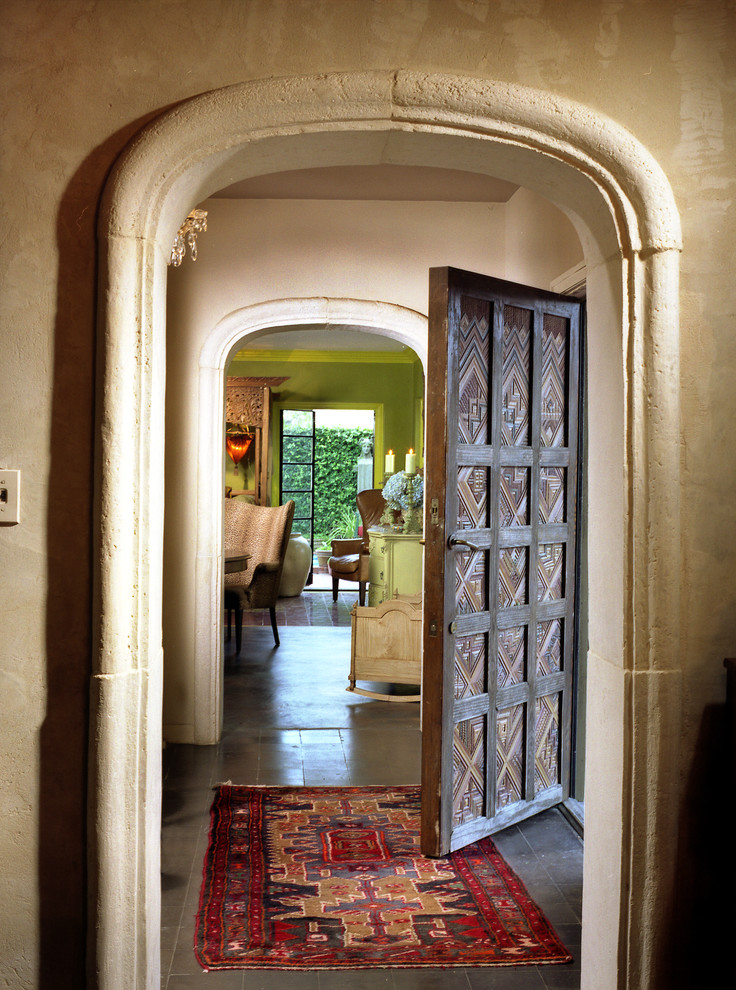 Imagen de distribuidor mediterráneo grande con paredes beige, suelo de cemento, puerta simple y puerta de madera oscura