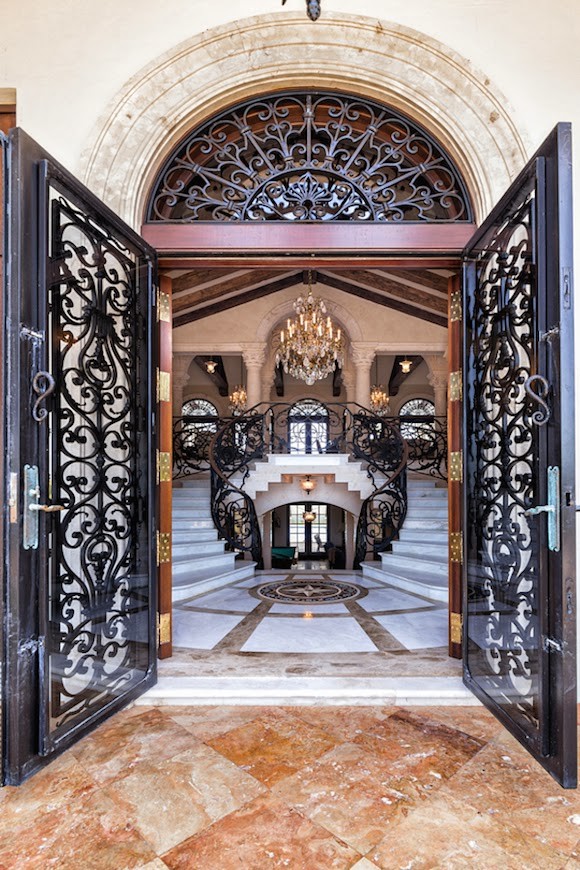 マイアミにあるラグジュアリーな巨大な地中海スタイルのおしゃれな玄関ロビー (ベージュの壁、磁器タイルの床、黒いドア、マルチカラーの床) の写真