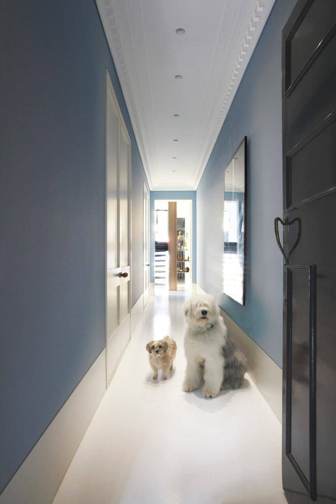 Inspiration pour une entrée design avec un mur bleu, un couloir, une porte simple, une porte noire et un sol blanc.