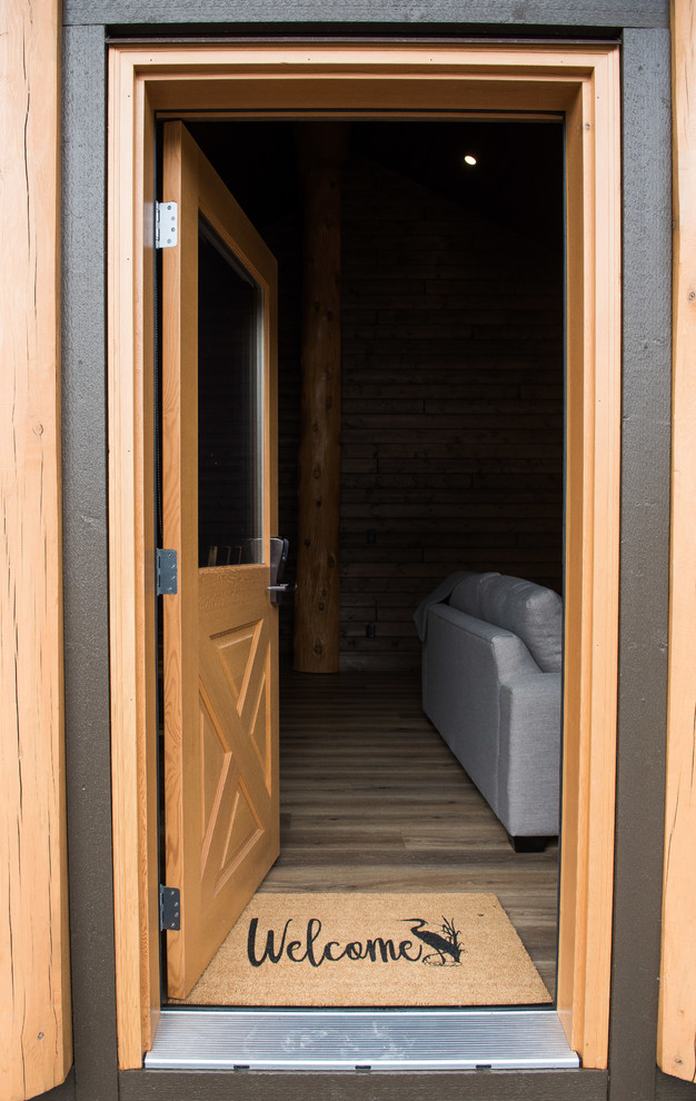 Imagen de puerta principal rústica pequeña con paredes marrones, suelo laminado, puerta simple, puerta de madera clara y suelo marrón