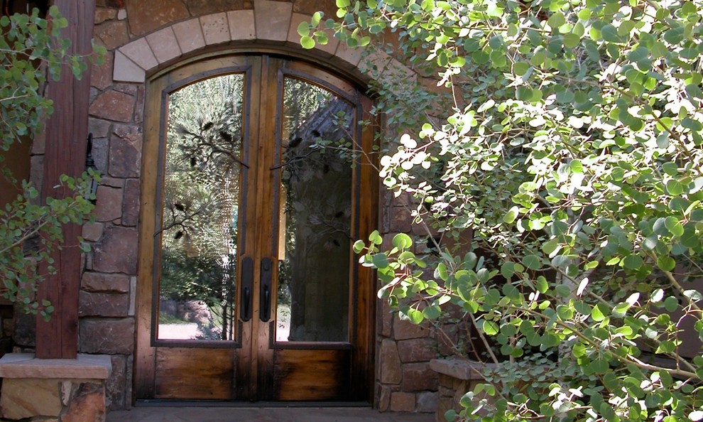 Modelo de puerta principal rústica grande con paredes beige, suelo de madera en tonos medios, puerta doble y puerta de madera en tonos medios
