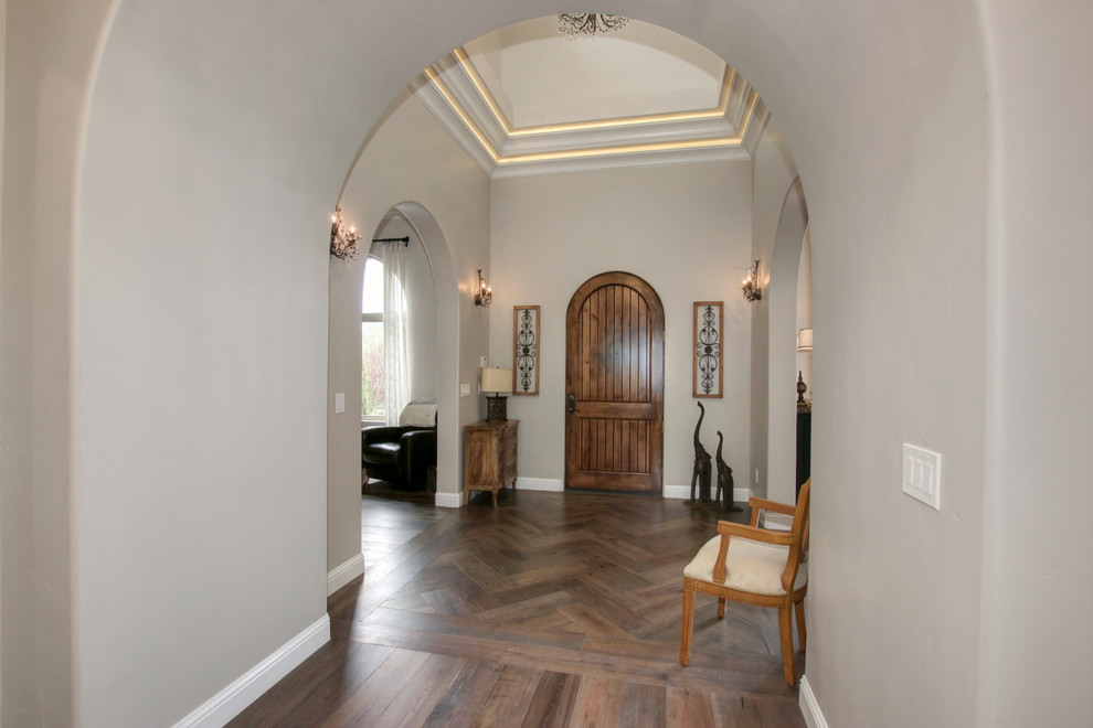 Mittelgroßer Mediterraner Eingang mit Vestibül, grauer Wandfarbe, hellem Holzboden, Einzeltür, hellbrauner Holzhaustür und braunem Boden in Sacramento