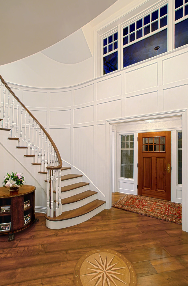 Exemple d'une grande entrée chic avec un couloir, un mur blanc, un sol en bois brun, une porte simple et une porte en bois brun.