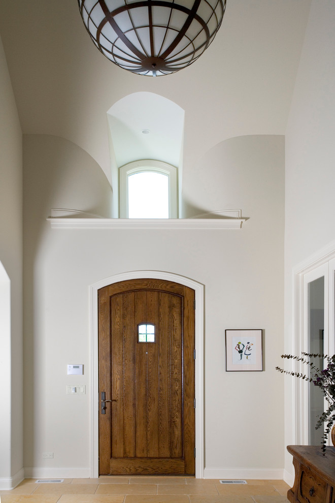Идея дизайна: большое фойе в стиле неоклассика (современная классика) с бежевыми стенами, полом из известняка, одностворчатой входной дверью и входной дверью из дерева среднего тона