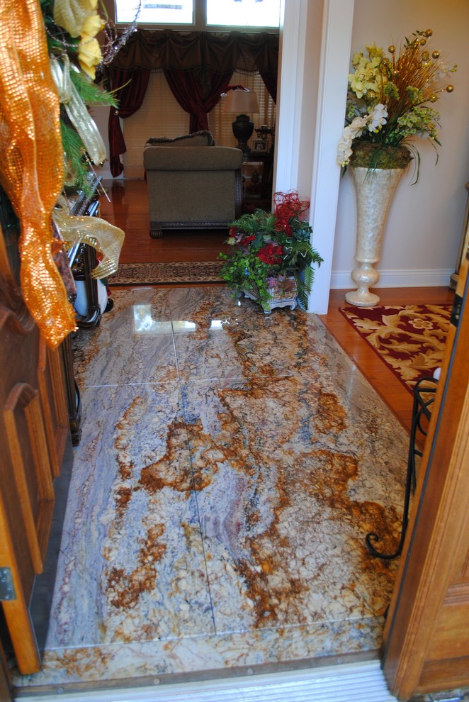 Example of a large classic granite floor entryway design in New Orleans with white walls and a medium wood front door