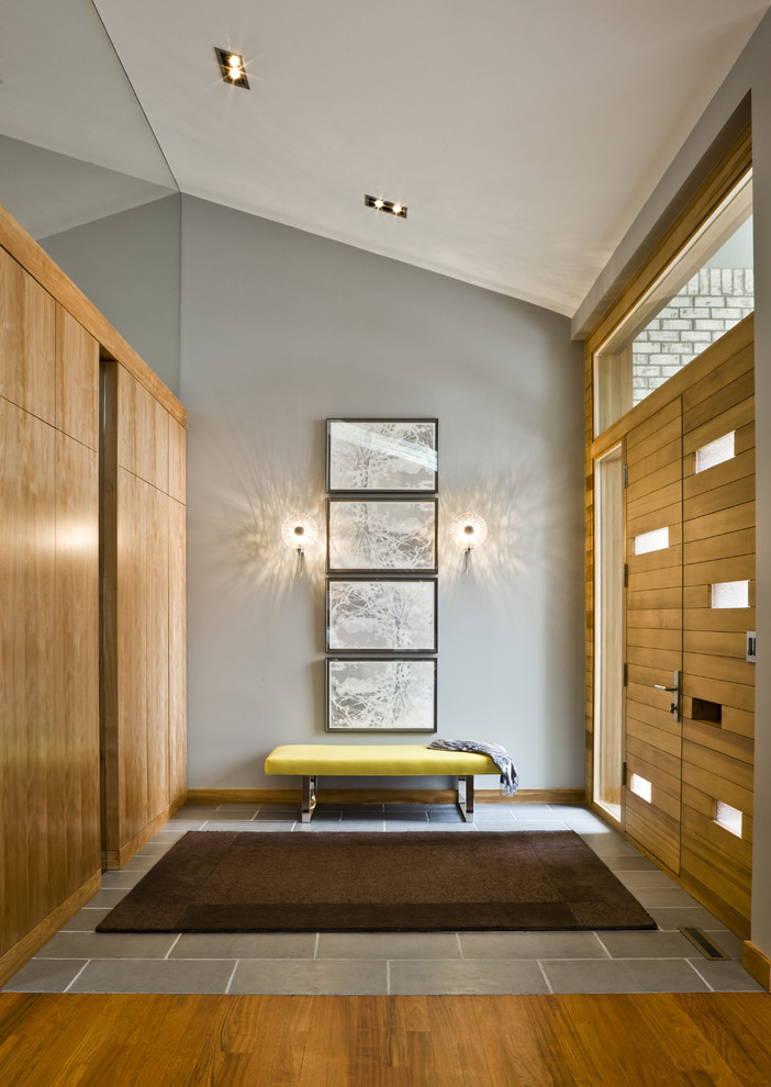 Modelo de entrada minimalista con paredes grises, puerta doble y puerta de madera en tonos medios