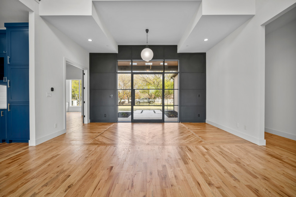 Mittelgroßes Modernes Foyer mit schwarzer Wandfarbe, hellem Holzboden, Drehtür, schwarzer Haustür, beigem Boden und vertäfelten Wänden in Dallas