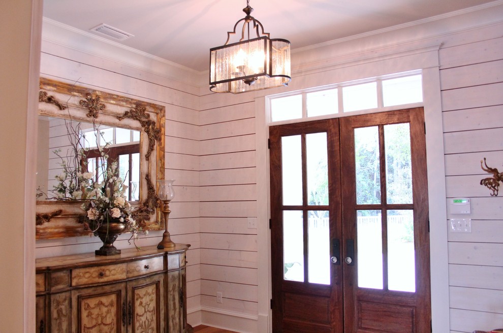 他の地域にあるおしゃれな玄関ロビー (白い壁、淡色無垢フローリング、濃色木目調のドア) の写真