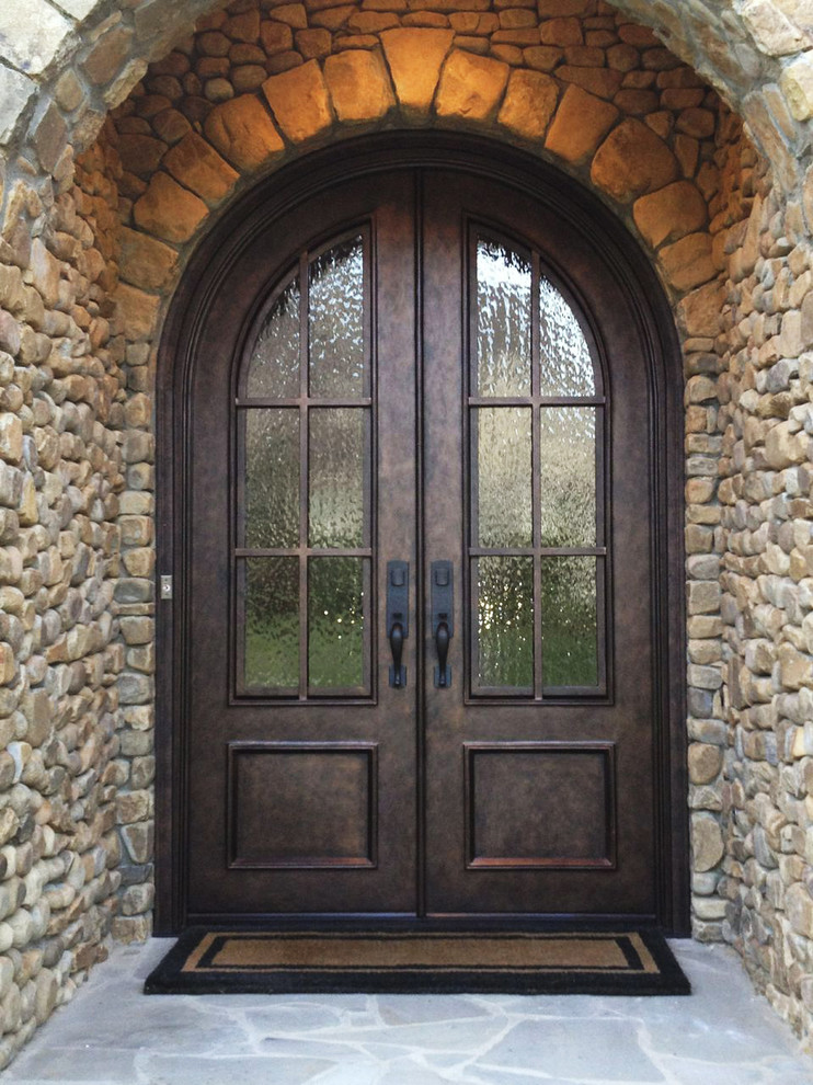 Imagen de puerta principal tradicional grande con puerta doble, paredes multicolor, puerta marrón y ladrillo