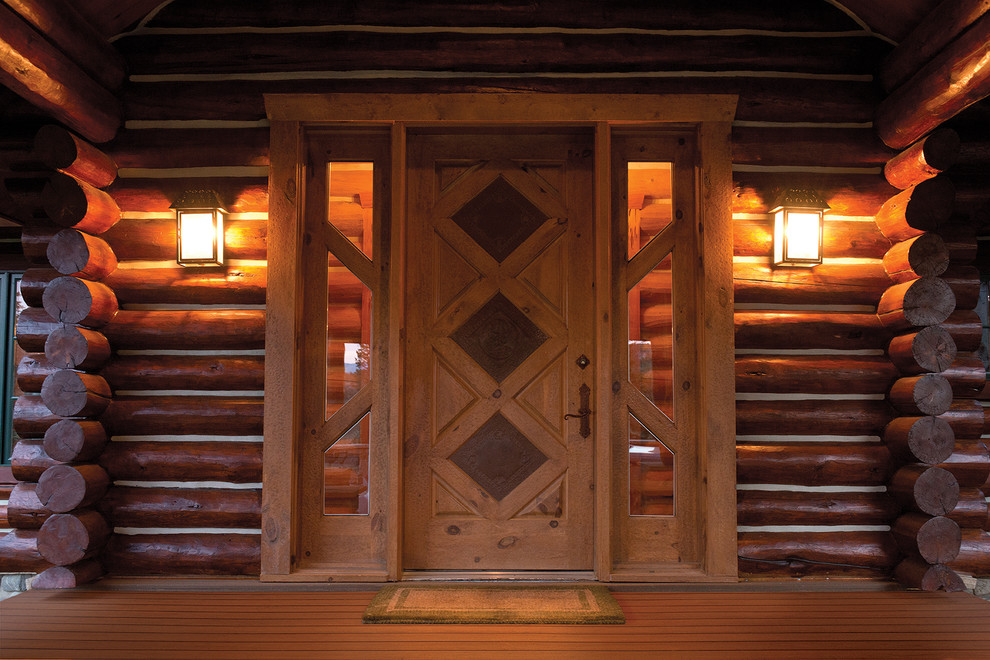 Exemple d'une grande porte d'entrée montagne avec un mur marron, un sol en bois brun, une porte simple, une porte en bois clair et un sol multicolore.