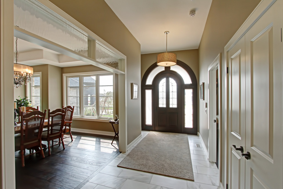 Mid-sized transitional porcelain tile and white floor entryway photo in Toronto with beige walls and a dark wood front door
