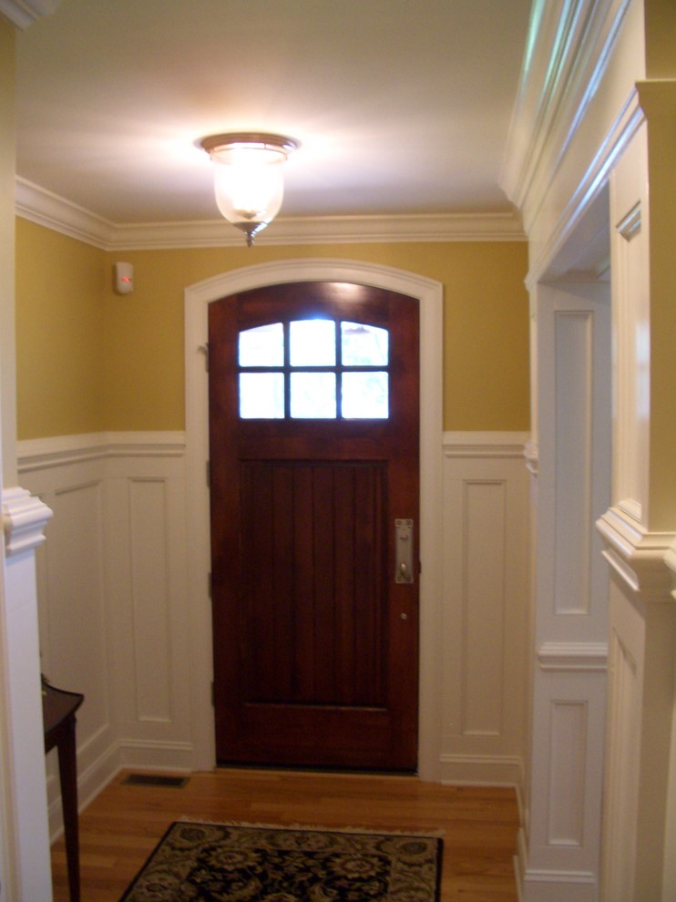 Foto di un grande ingresso chic con pareti beige, pavimento in legno massello medio, una porta singola e una porta in legno scuro