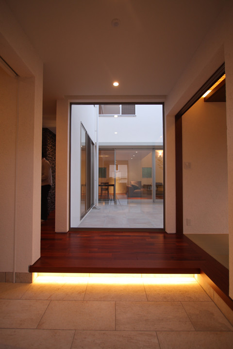 Aménagement d'une entrée moderne avec un couloir, un mur blanc, un sol en carrelage de céramique, une porte double, une porte en bois brun et un sol blanc.