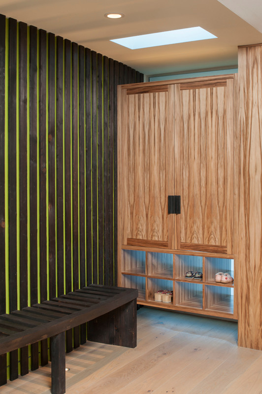 Imagen de distribuidor moderno con suelo de madera clara y puerta simple