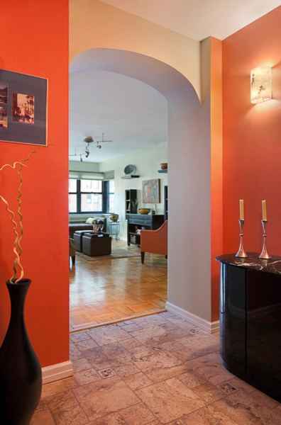 Example of a small eclectic marble floor entryway design in New York with orange walls