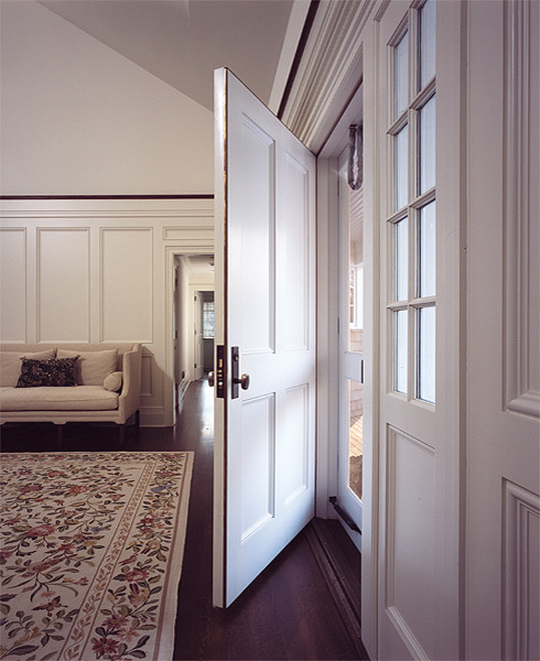 Diseño de distribuidor clásico con paredes blancas, suelo de madera oscura, puerta simple y puerta blanca