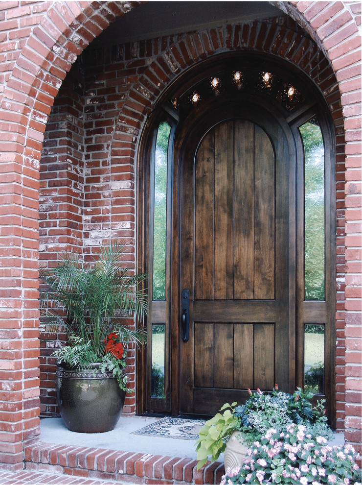 Ispirazione per una porta d'ingresso di medie dimensioni con pareti rosse, pavimento in cemento, una porta singola e una porta in legno scuro
