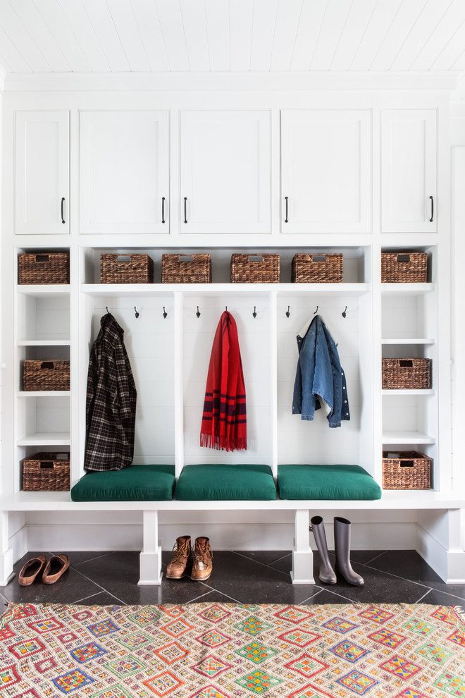 Large country boot room in New York with a stable front door, white walls, limestone flooring, a black front door and black floors.