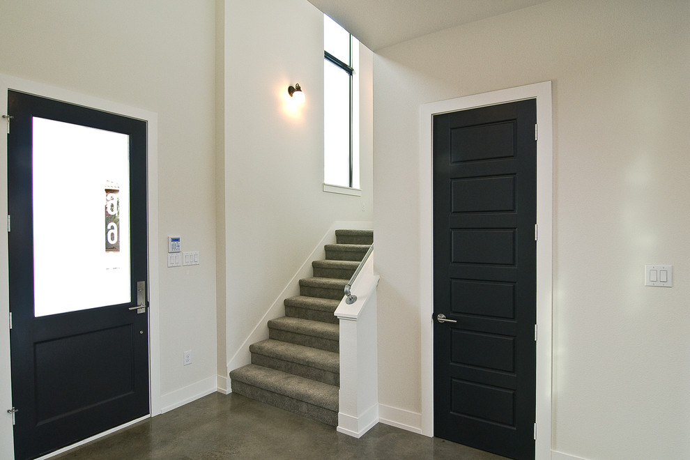 Idee per un ampio ingresso design con pareti bianche, pavimento in cemento, una porta singola e una porta grigia