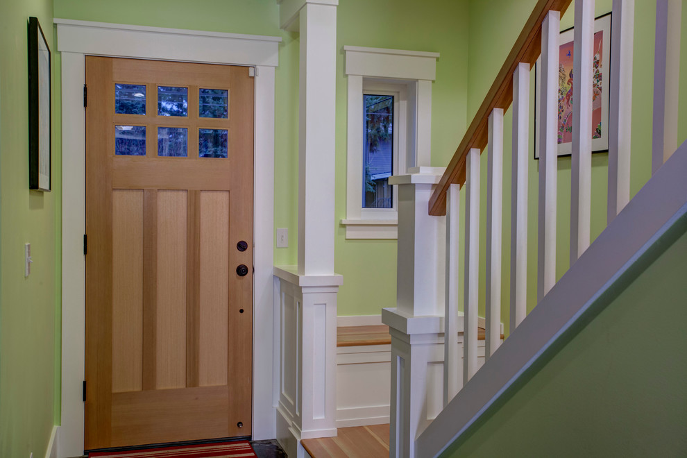 Immagine di un ingresso stile americano di medie dimensioni con pareti verdi, pavimento in legno massello medio, una porta singola e una porta in legno bruno