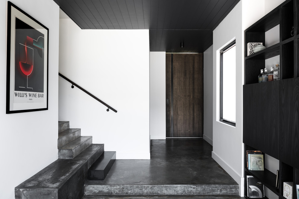 Inspiration pour une entrée design avec un couloir, un mur blanc, sol en béton ciré, une porte simple, une porte en bois foncé et un sol gris.