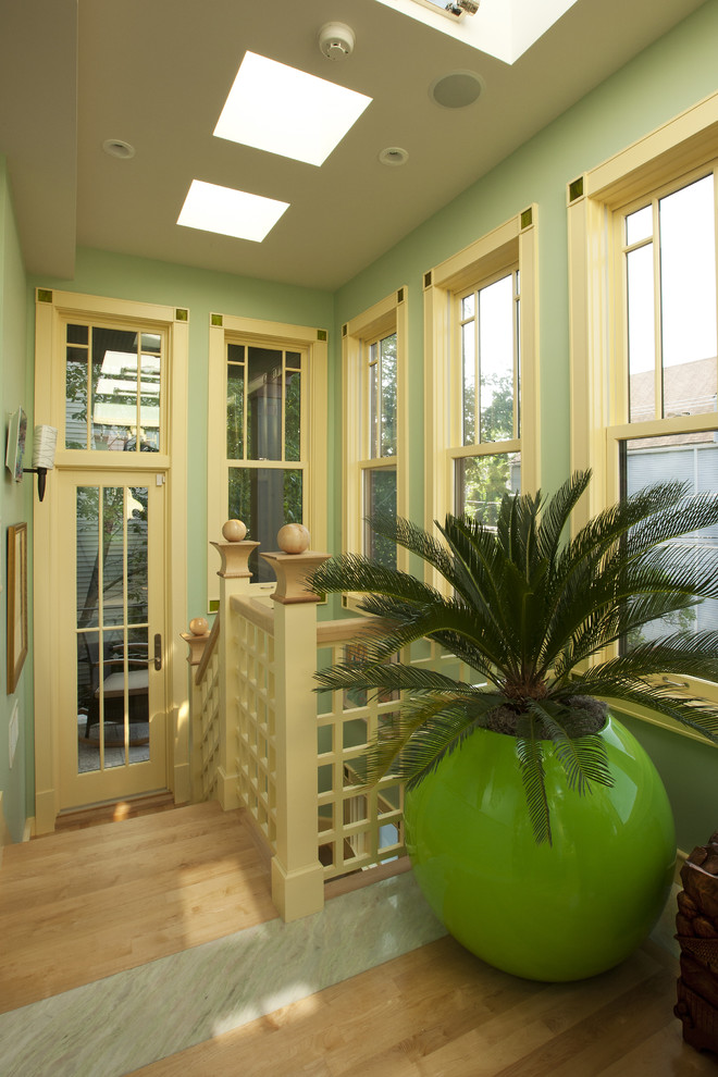 Inredning av en exotisk stor entré, med gröna väggar, en enkeldörr, glasdörr, ljust trägolv och flerfärgat golv