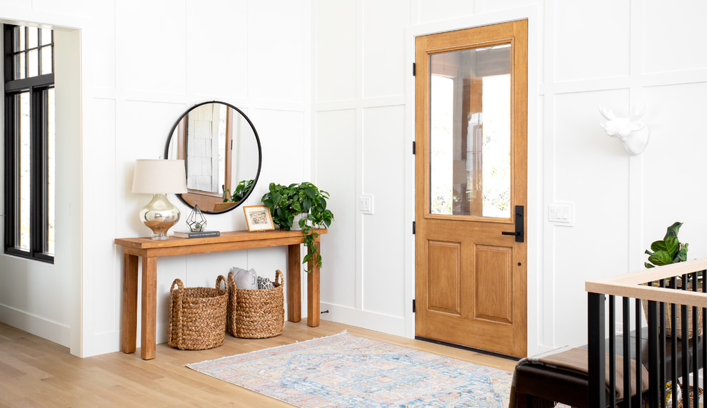 This is an example of a large farmhouse front door in Salt Lake City with light hardwood flooring, a single front door, a light wood front door, beige floors and feature lighting.