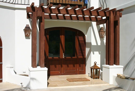 Diseño de puerta principal tropical extra grande con paredes blancas, suelo de travertino, puerta doble, puerta de madera oscura y suelo marrón