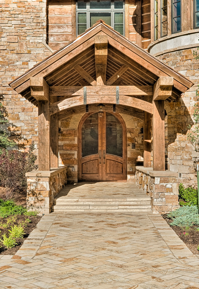 Idee per un grande ingresso o corridoio rustico con una porta a due ante, pareti marroni, pavimento in pietra calcarea e una porta in vetro