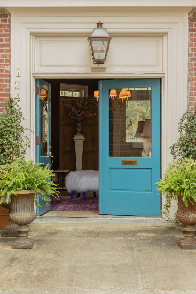 Cette image montre une entrée bohème avec une porte double, une porte bleue et sol en béton ciré.