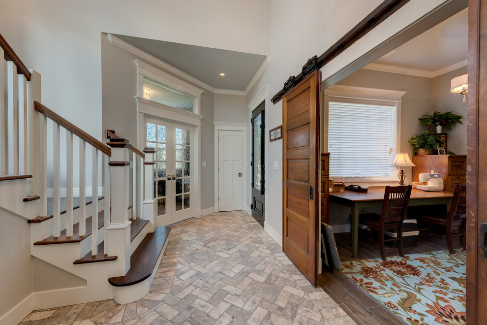 Example of a mid-sized arts and crafts travertine floor and brown floor entryway design in Other with gray walls and a black front door