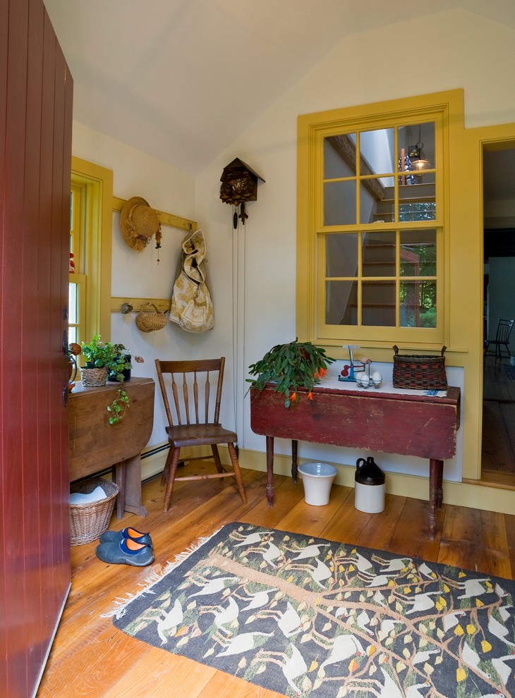 Exemple d'une entrée chic de taille moyenne avec un vestiaire, un mur blanc, un sol en bois brun, une porte simple et une porte rouge.