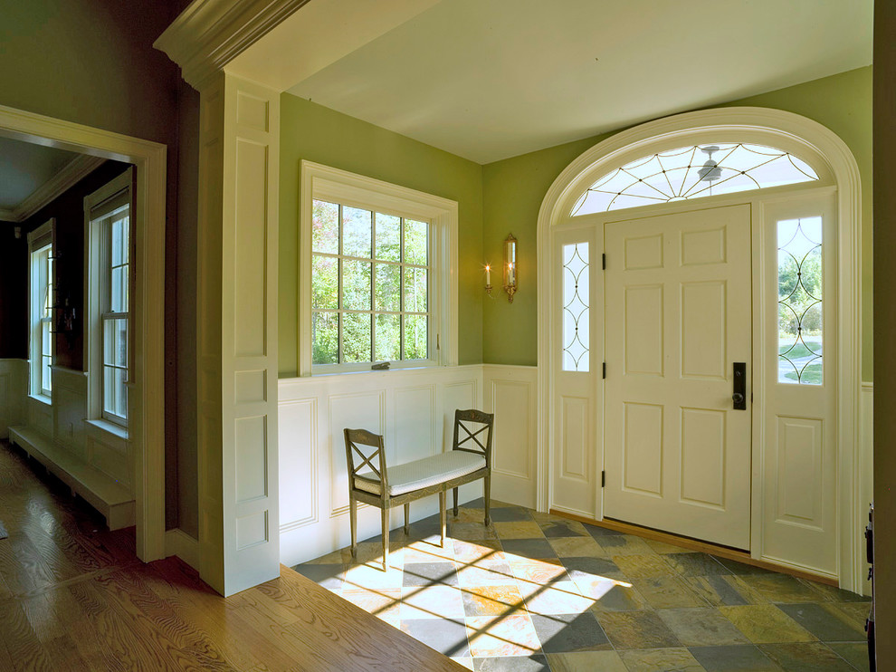 На фото: большое фойе в классическом стиле с разноцветными стенами, полом из травертина, одностворчатой входной дверью и желтой входной дверью с