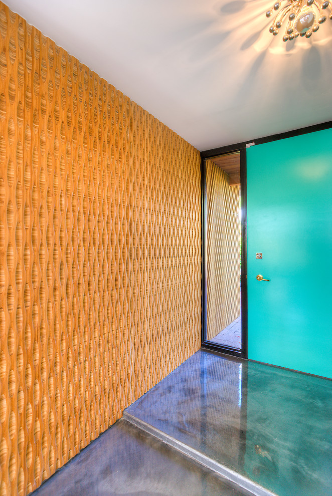 Cette image montre une porte d'entrée minimaliste de taille moyenne avec sol en béton ciré, une porte simple, un mur multicolore et une porte verte.