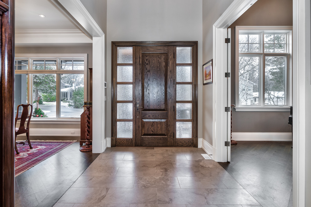 トロントにある広いトランジショナルスタイルのおしゃれな玄関ロビー (グレーの壁、磁器タイルの床、濃色木目調のドア、ベージュの床) の写真