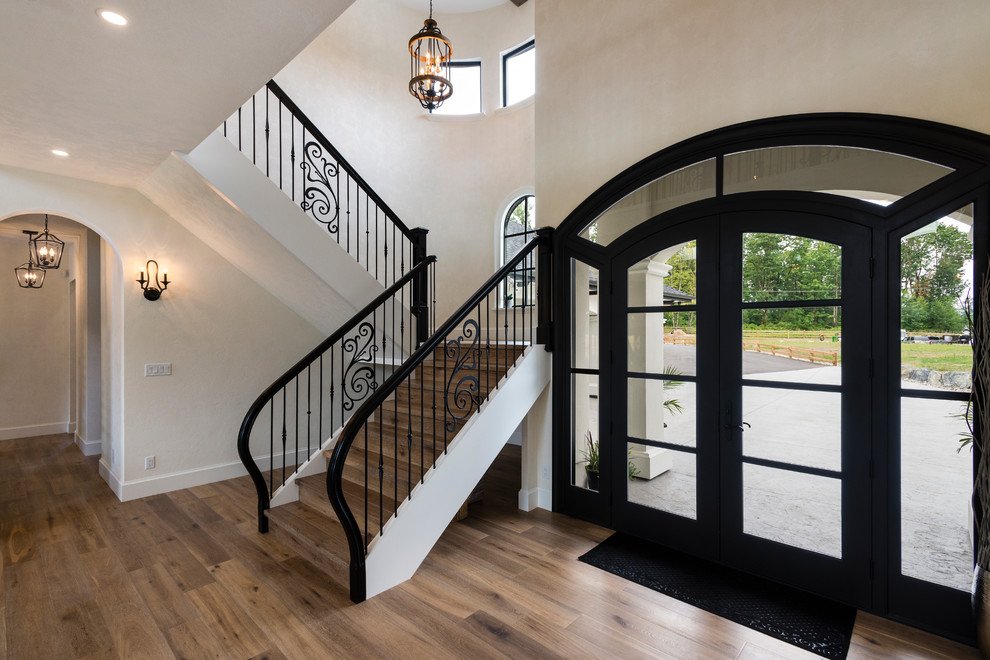 Ispirazione per un grande ingresso classico con pareti bianche, pavimento in legno massello medio, una porta a due ante, una porta nera e pavimento marrone