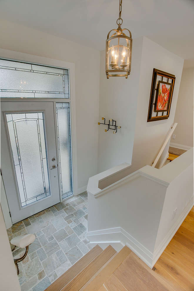 トロントにある高級な小さなトランジショナルスタイルのおしゃれな玄関ロビー (白い壁、ライムストーンの床、ガラスドア、マルチカラーの床) の写真