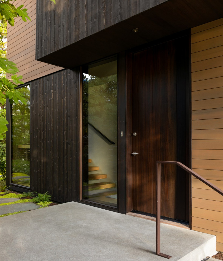Modelo de entrada actual con suelo de madera en tonos medios, puerta simple, puerta de madera oscura y madera