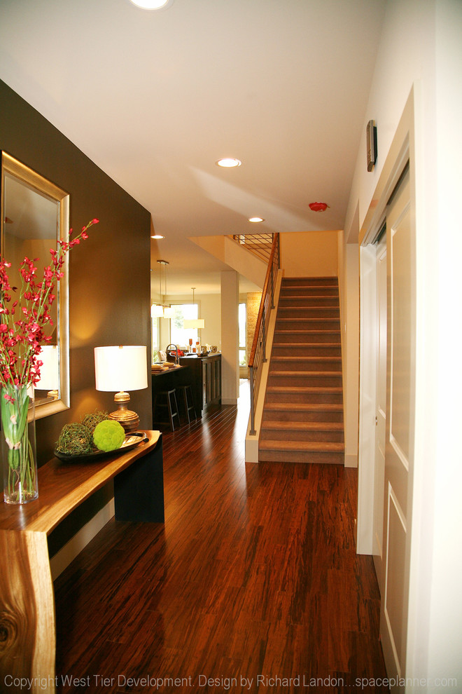 Exemple d'une grande entrée tendance avec un couloir, un mur blanc et un sol en bois brun.