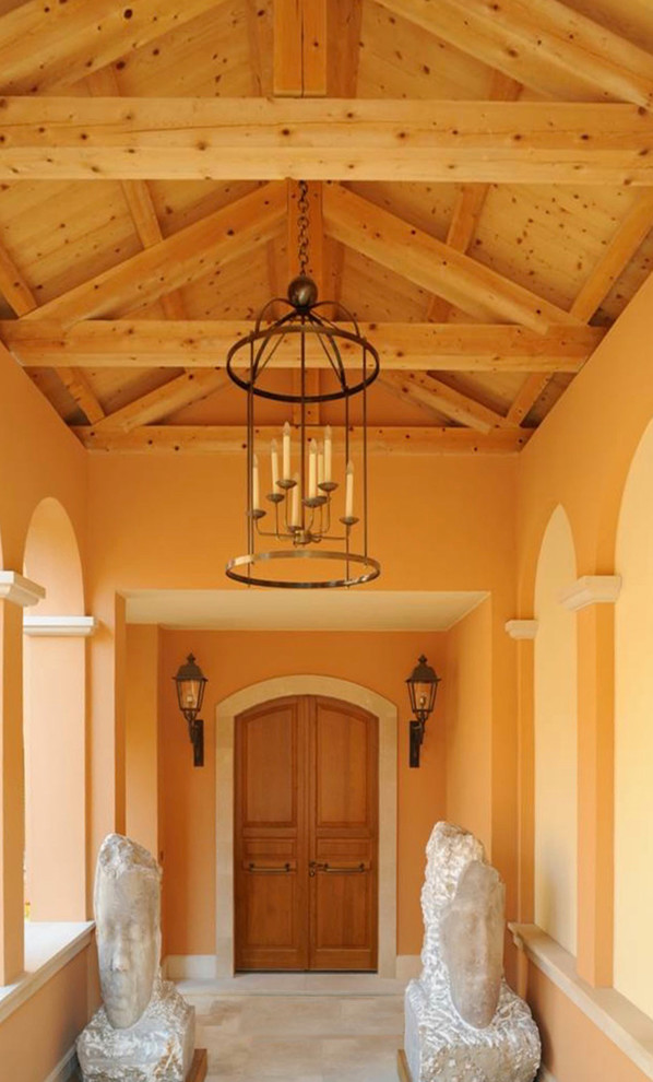 Ispirazione per un'ampia porta d'ingresso mediterranea con pareti rosa, pavimento in pietra calcarea, una porta a due ante, una porta in legno chiaro e pavimento beige