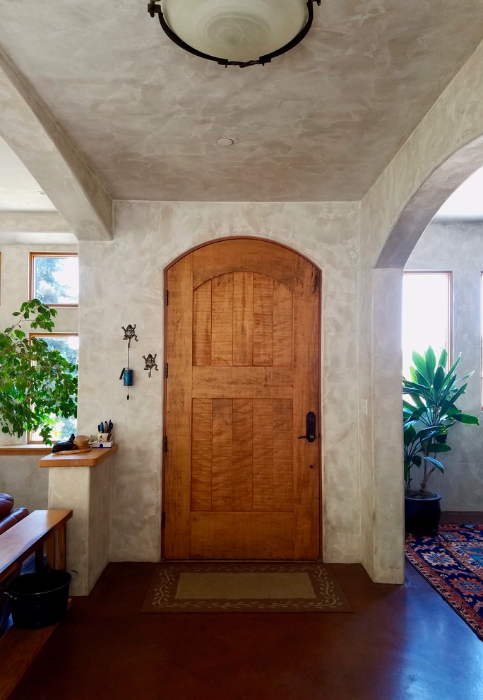 Diseño de puerta principal mediterránea pequeña con paredes beige, puerta simple, puerta de madera en tonos medios, suelo marrón y suelo de cemento